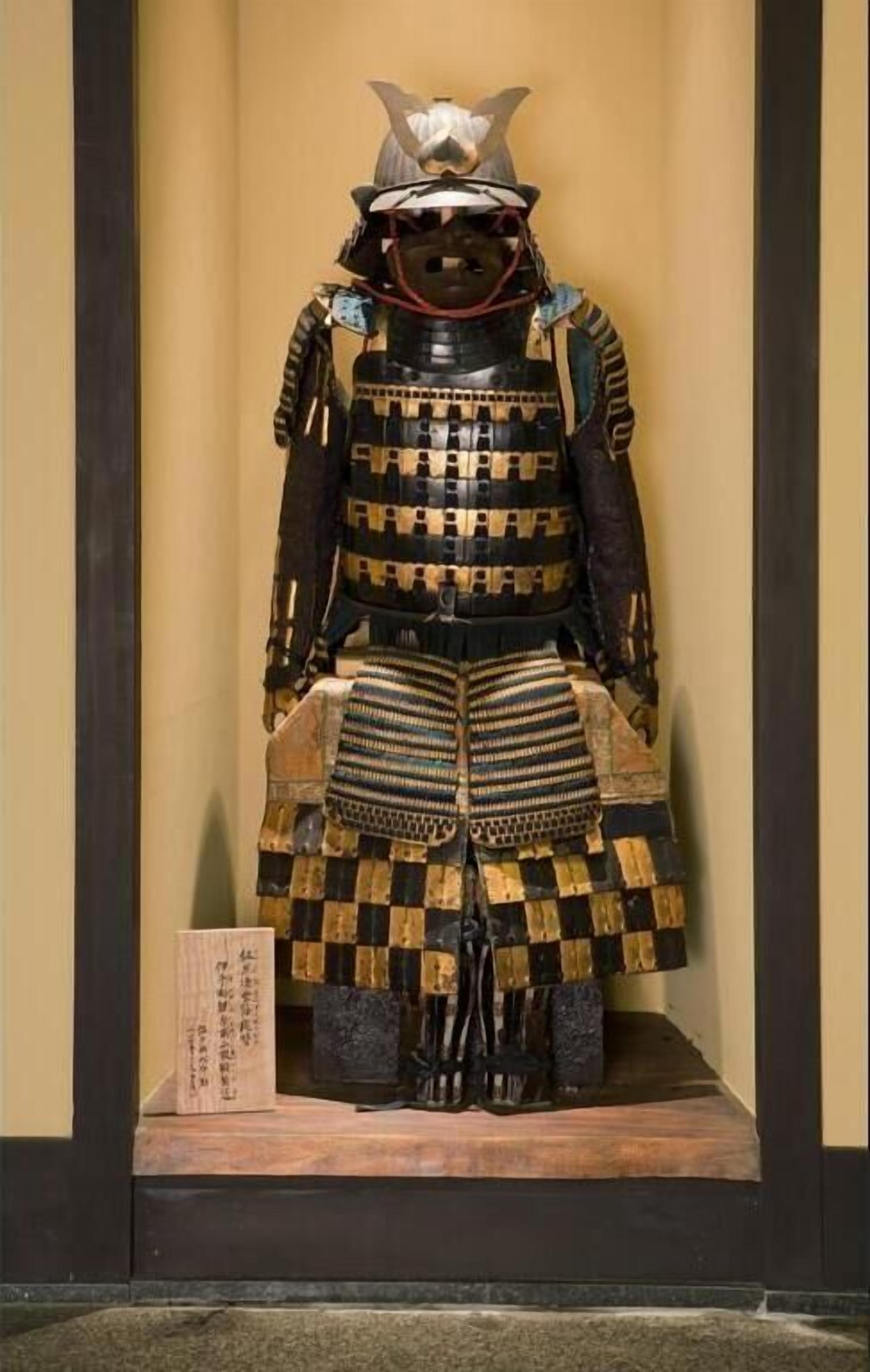 A display of a traditional samurai armor with a helmet, chest plate, and leg guards.