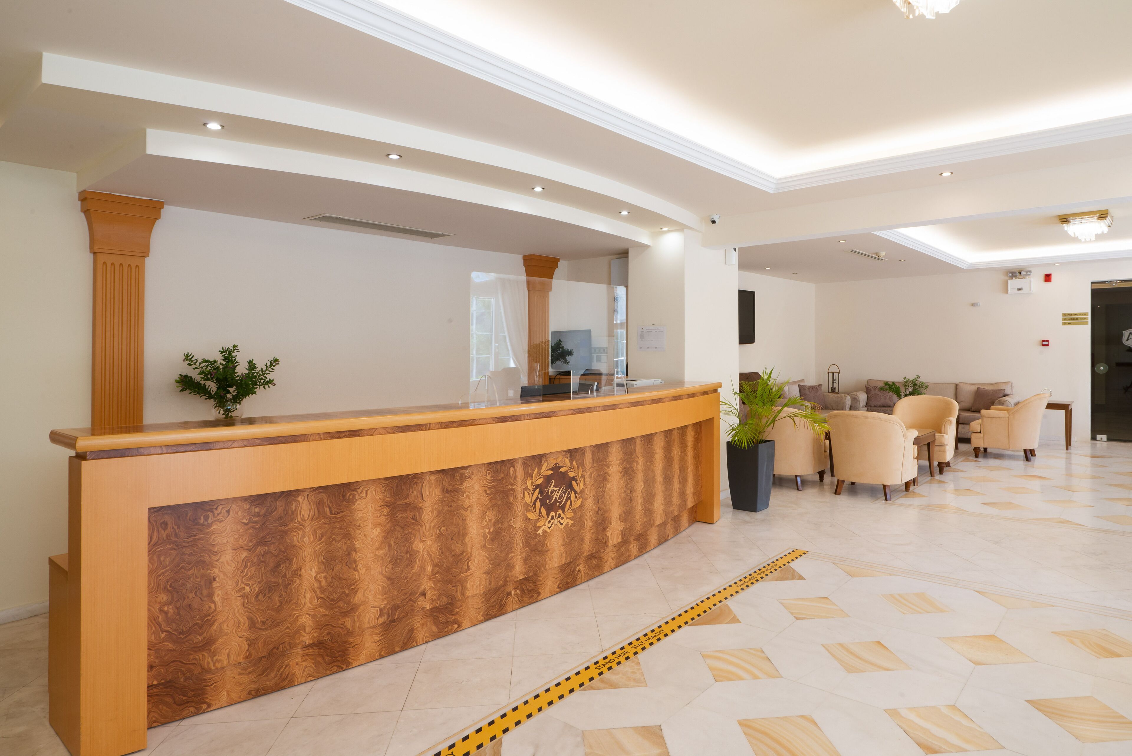 A reception area with a wooden reception desk, a seating area with beige chairs, and a tiled floor.
