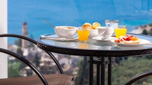 A table with breakfast items and a glass of orange juice, overlooking a scenic view.