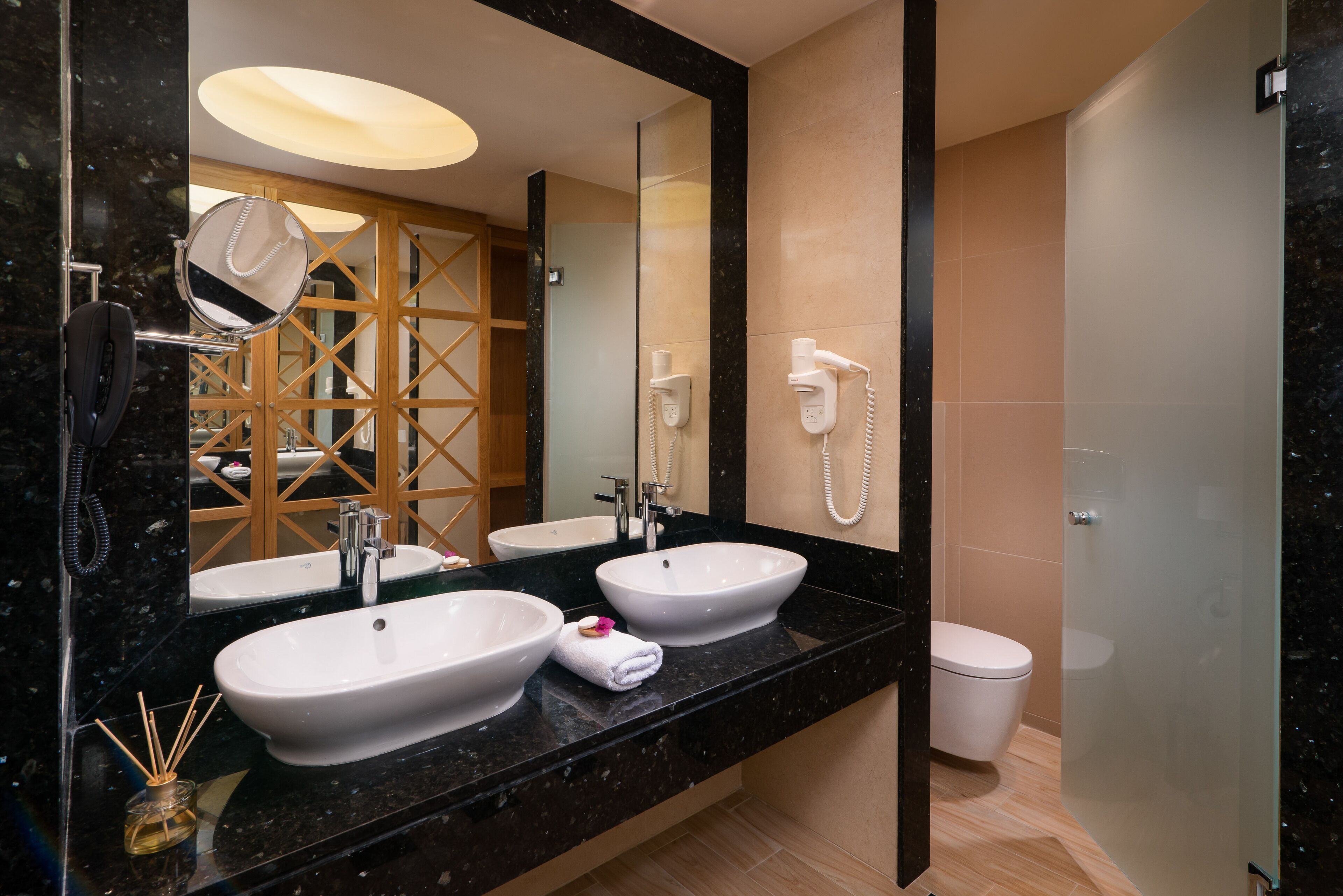 A modern bathroom with two sinks, a large mirror, and a glass shower enclosure.