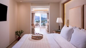 A hotel room with a bed, a bedside table with a lamp, a view of the balcony, and a dining area.