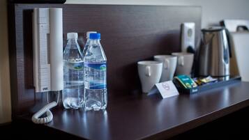Un mostrador de recepción de hotel con dos botellas de agua, un teléfono y una cafetera.