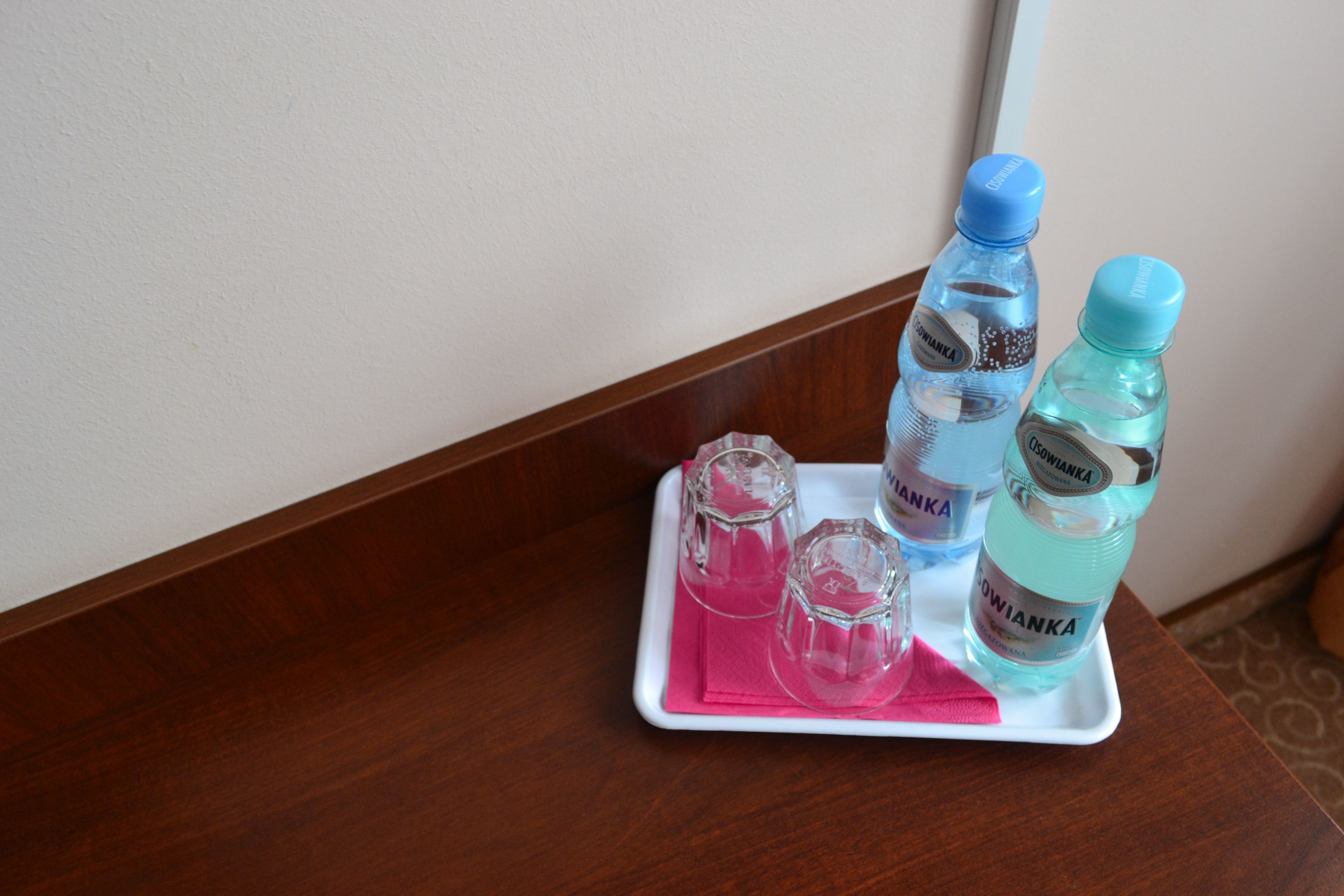 Un plateau avec deux bouteilles d’eau et trois verres, posé sur une table en bois.