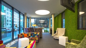 A modern lobby with large windows, colorful seating, and a green wall. - Boutique Hotel's Kwiska / Legnicka (Wroclaw)