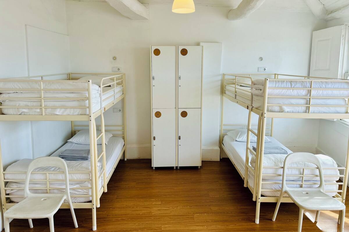 A dormitory room with bunk beds, a wardrobe, and a desk.