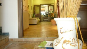 Eine Hotelhalle mit einer Rezeption, einer Couch und einer großen Vase mit dem Namen "Tiziana".