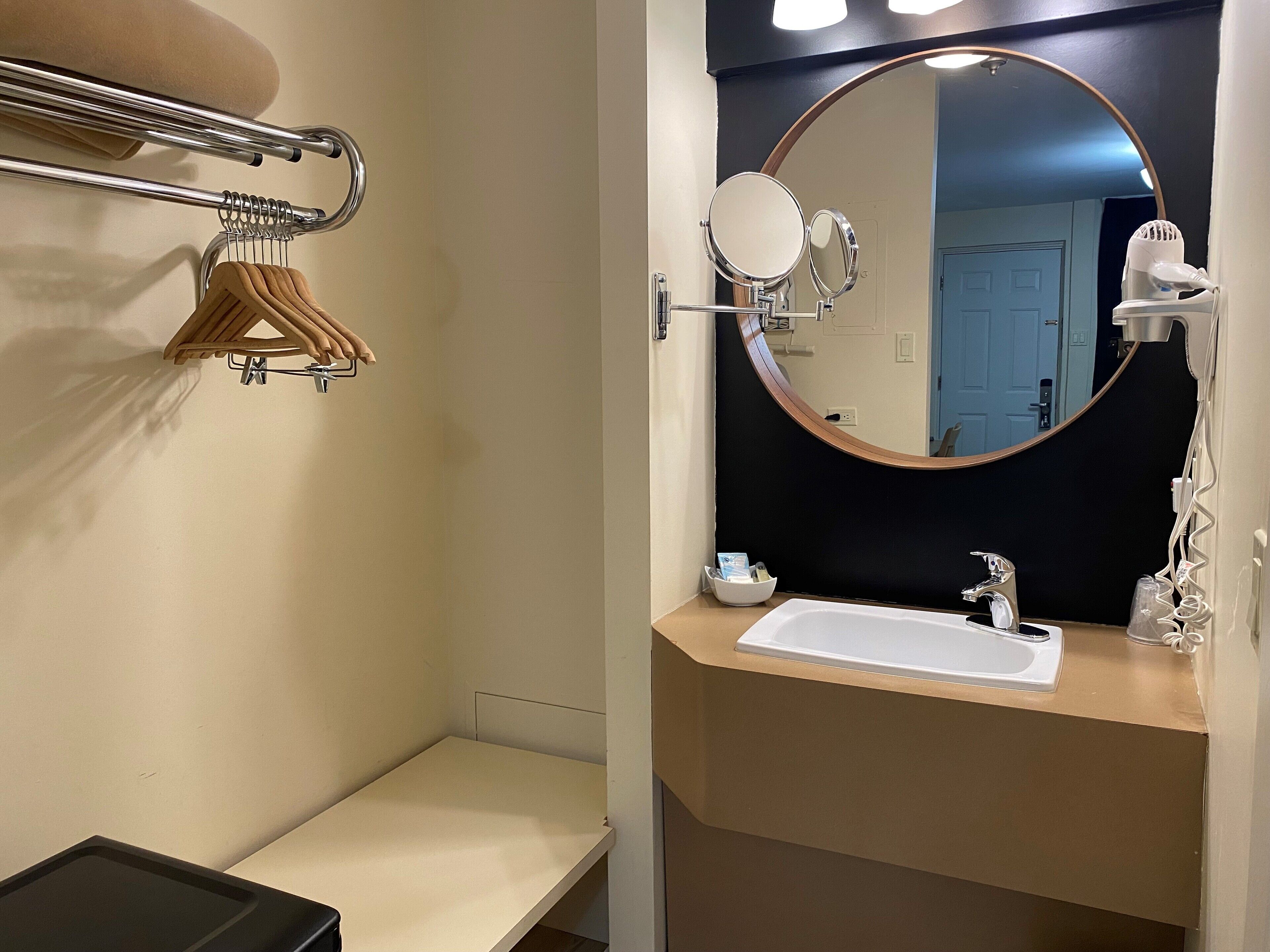 Un baño con un lavabo blanco, un espejo redondo, un perchero y un secador de pelo.