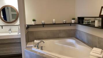 A modern bathroom with a freestanding bathtub, a vanity with a mirror, and a shelf with decorative items.