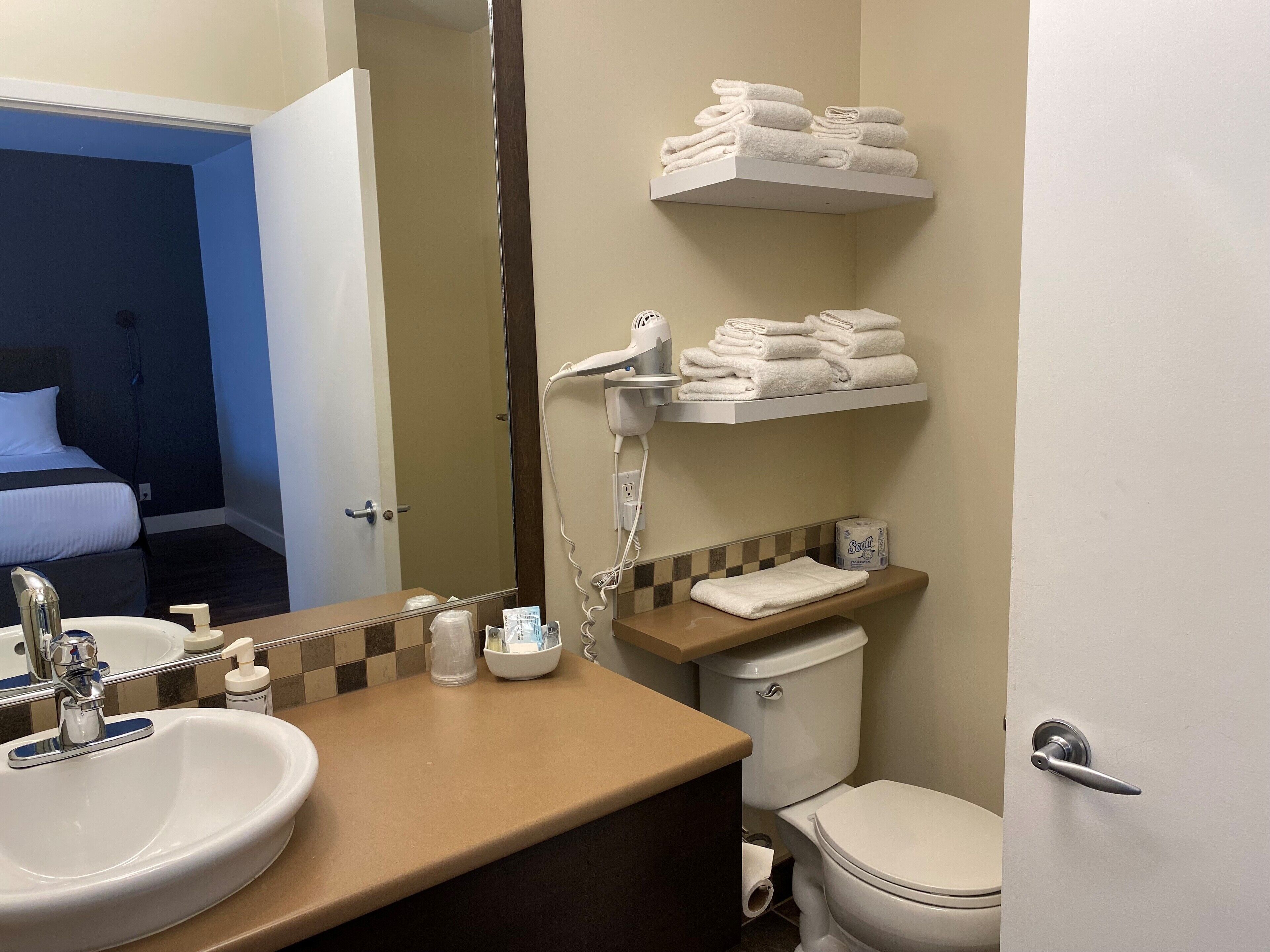 Un baño con lavamanos, inodoro, toallero y espejo.