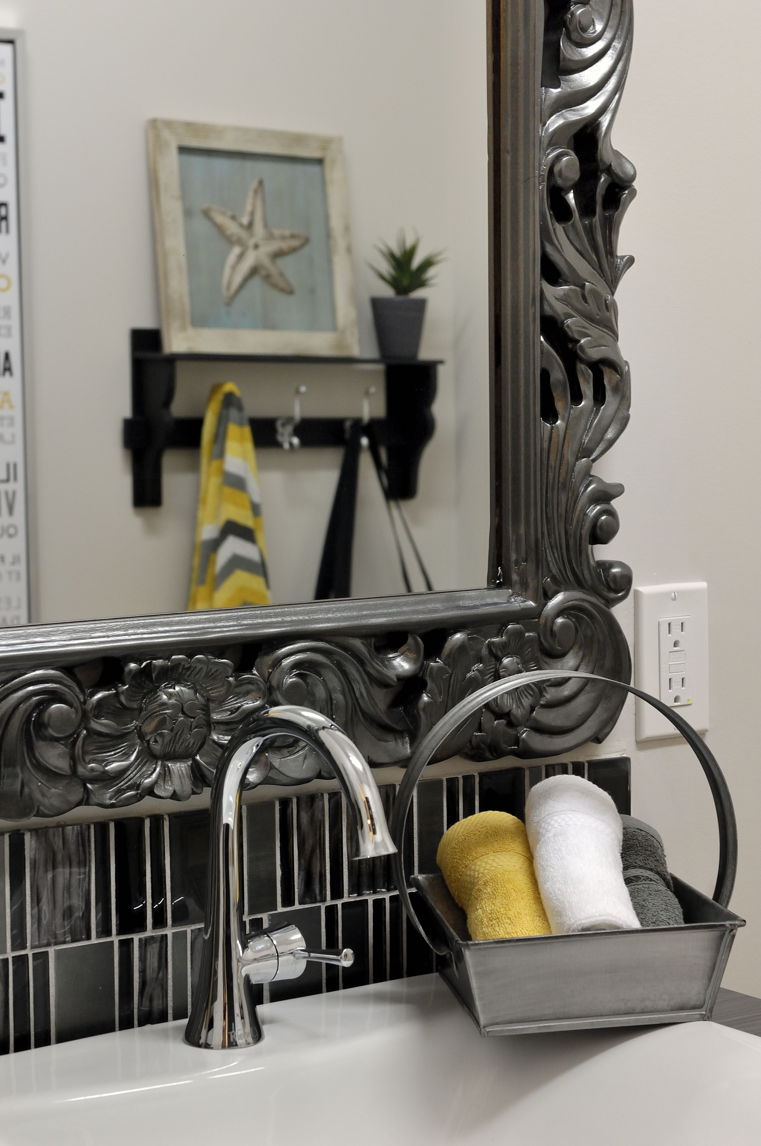 Un baño con un espejo decorativo, un lavamanos y un toallero con toallas.