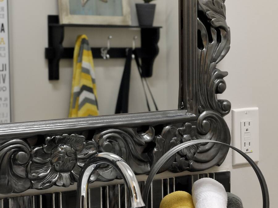 Un baño con un espejo decorativo, un lavamanos y un toallero con toallas.