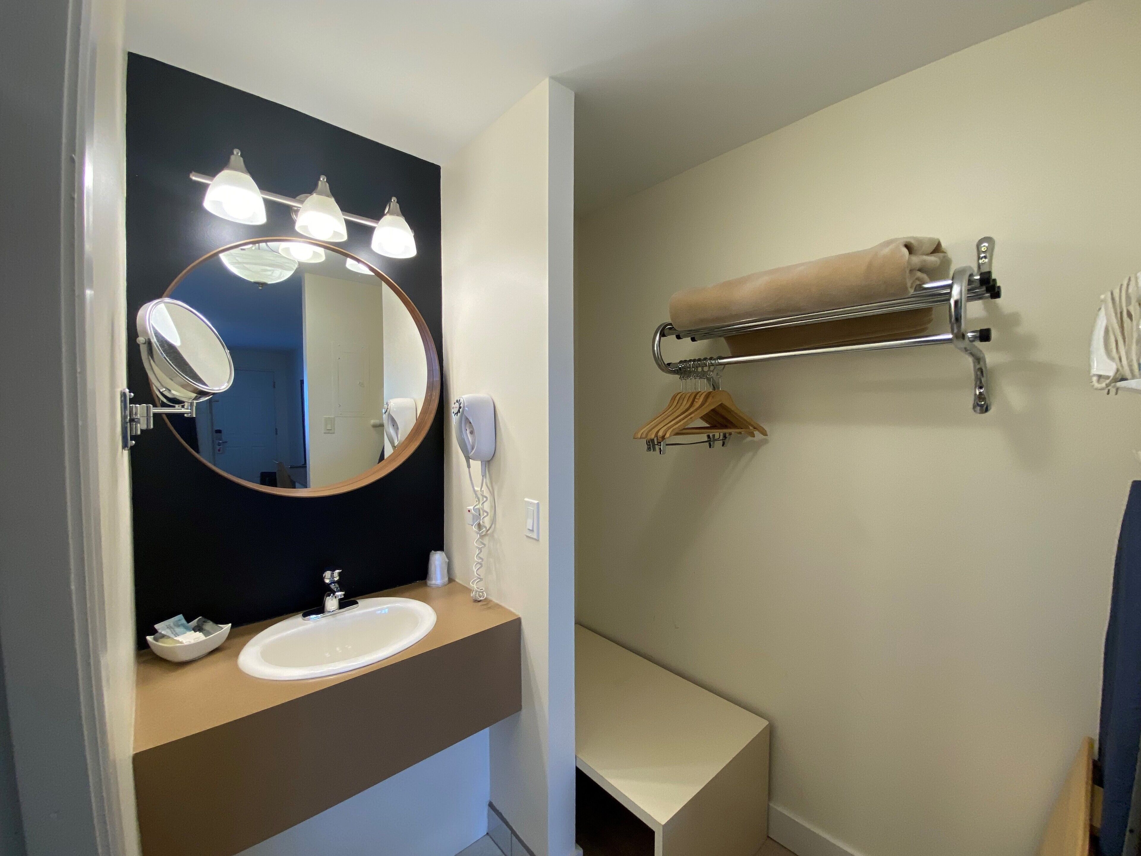 A bathroom with a round mirror, a sink, a towel rack, and a towel hanging on the rack.