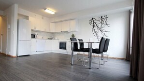 Una cocina moderna con armarios blancos, una mesa de comedor con sillas y una obra de arte decorativa.