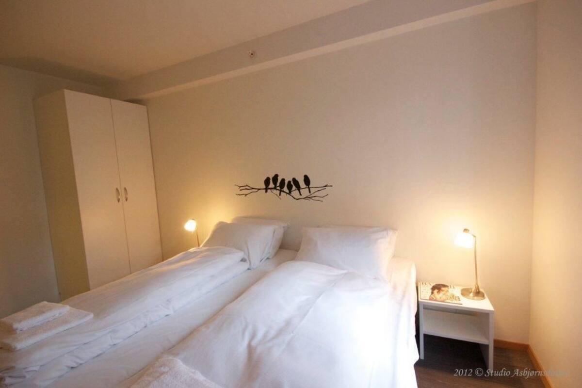 Ein Doppelbett mit weißer Bettwäsche, ein Nachttisch mit Lampe und ein Kleiderschrank.