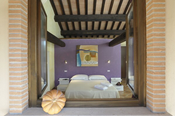 Un dormitorio con cama, un ventanal amplio, una calabaza decorativa y un cuadro en la pared.
