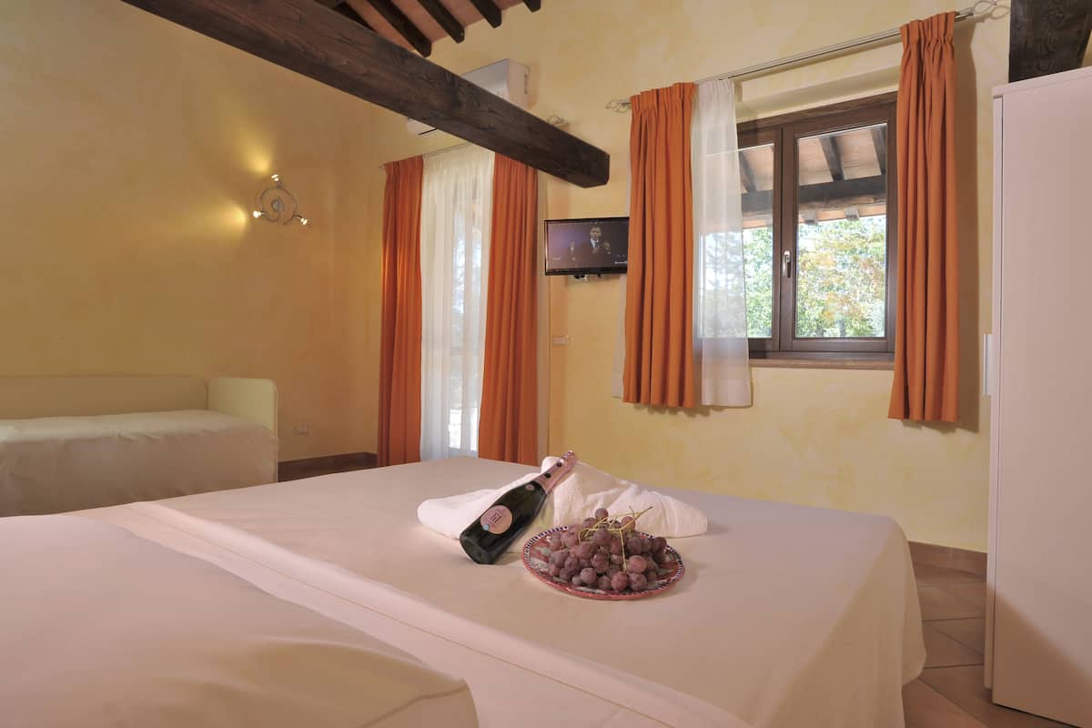 A hotel room with a bed, a bottle of champagne, and a plate of grapes.