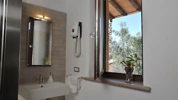 Ein modernes Badezimmer mit einem großen Spiegel, einem Waschbecken und einem Fenster mit Blick auf Bäume.