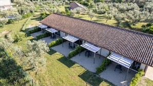 Een villa met pannendak, zonnepanelen en een patio met buitenmeubilair.