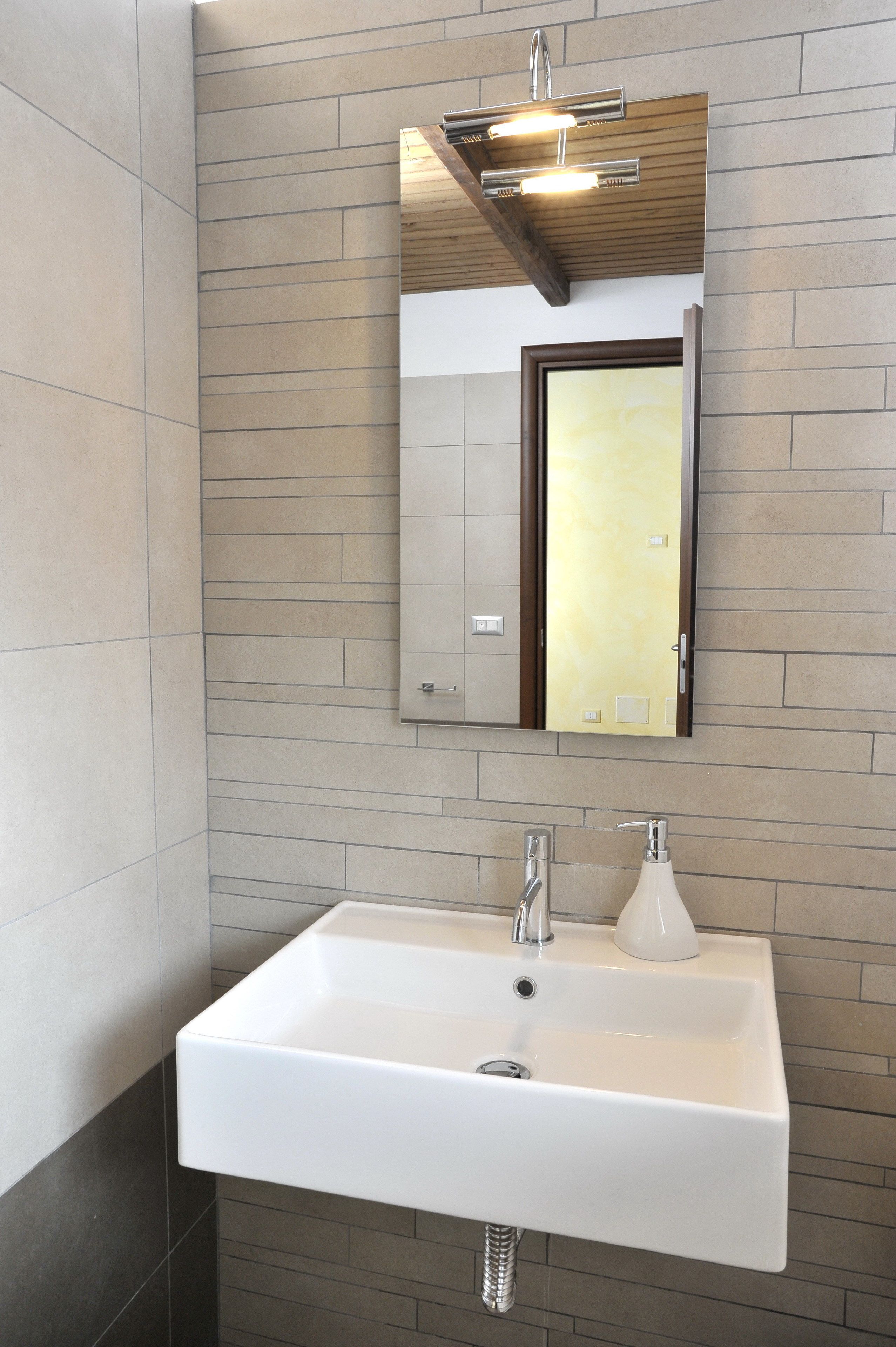A bathroom with a white sink, a mirror, and a wooden ceiling.