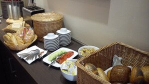 Een buffet met diverse gerechten, waaronder brood, boter en toevoegingen.