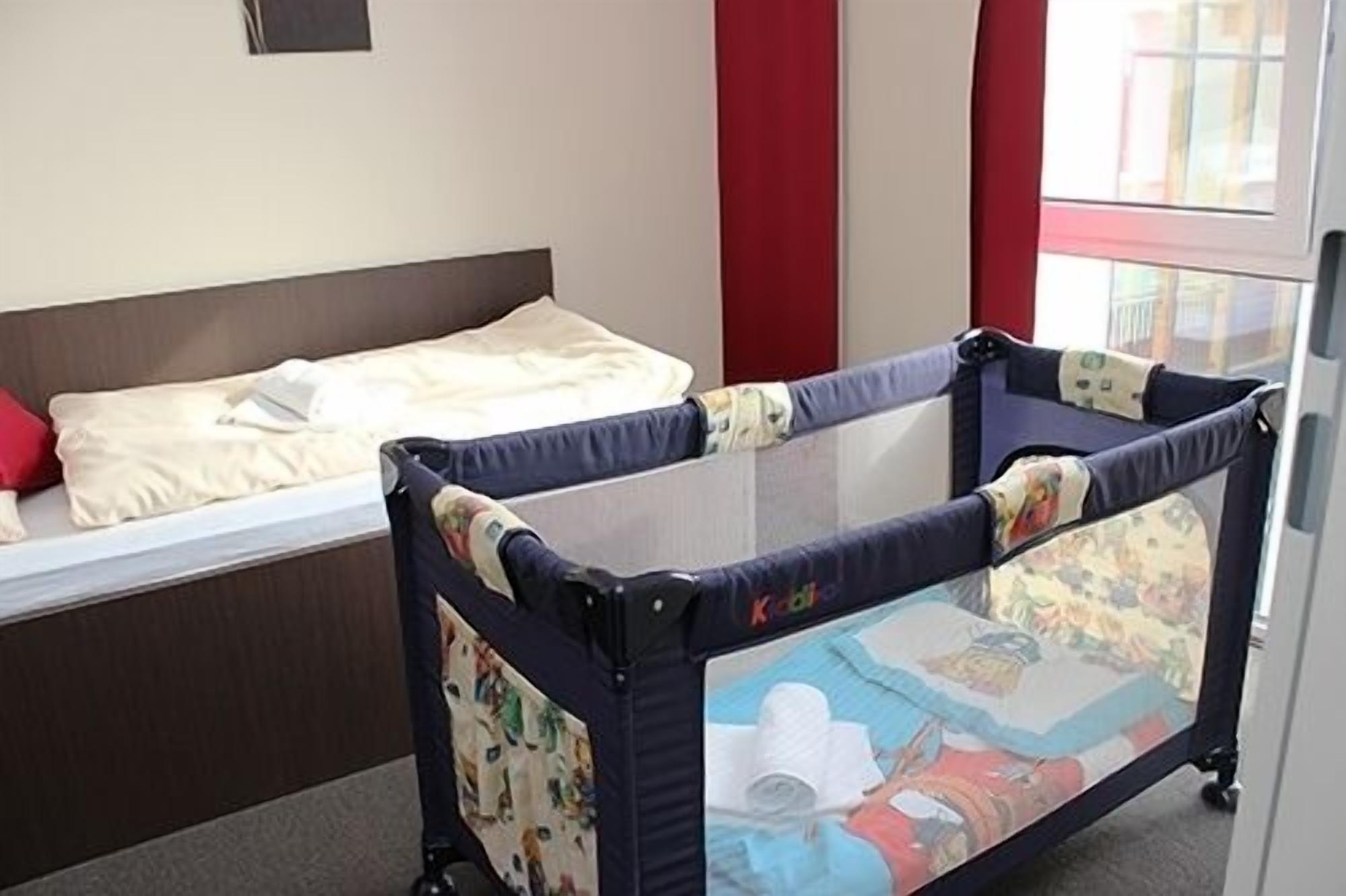 A room with a bed, a crib, and a window.