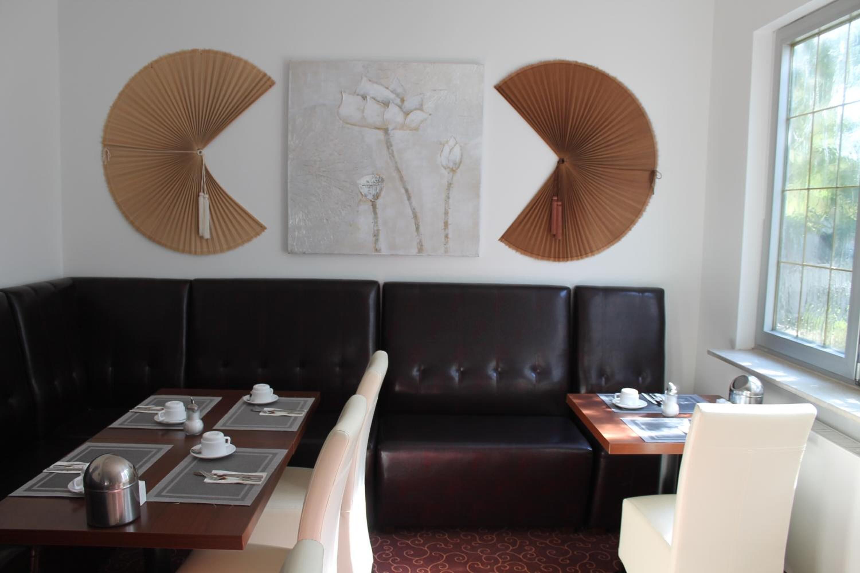 A dining area with a booth seating arrangement, a table set with white tableware, and two wall-mounted fans.