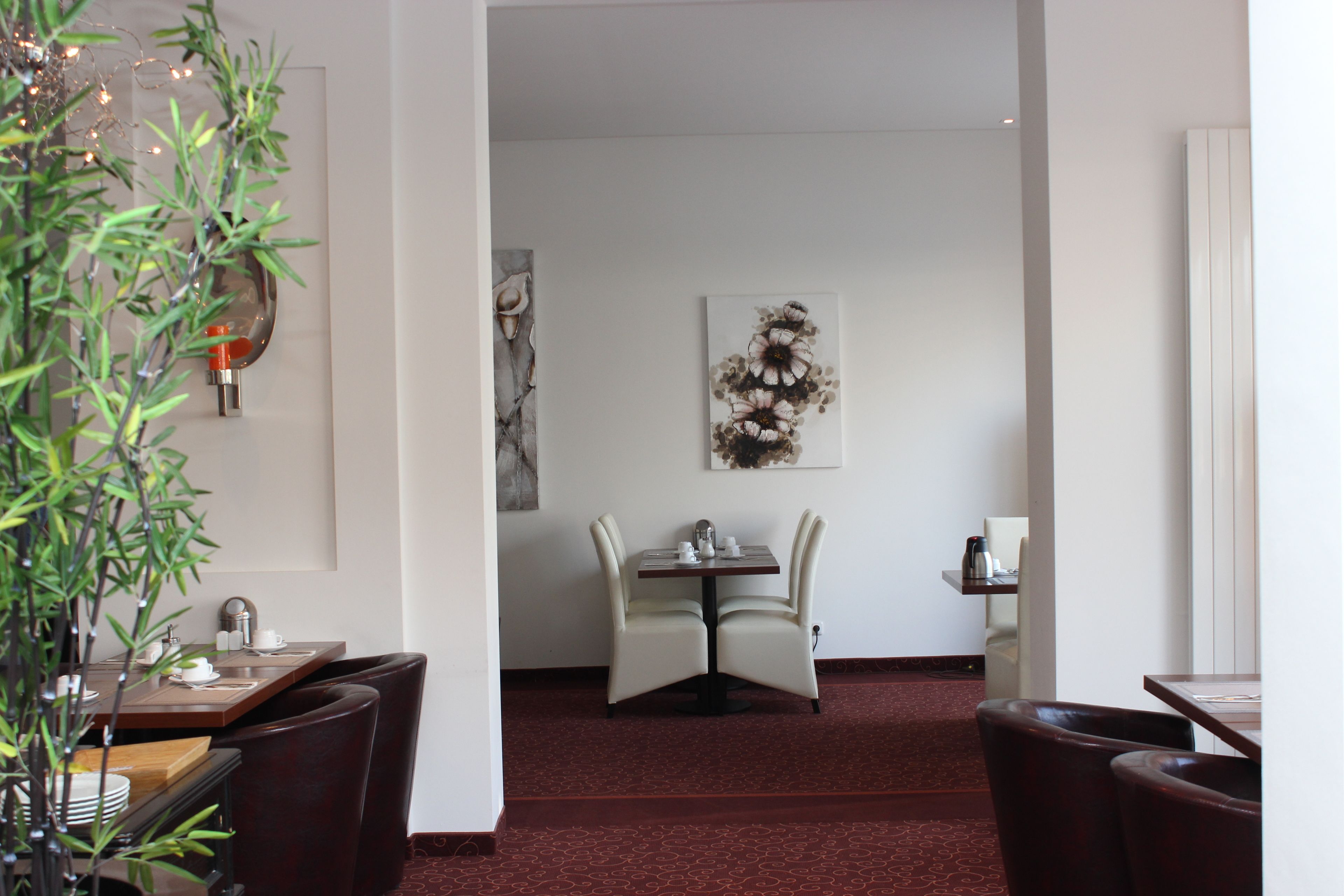 A dining area with a table and chairs, a vase with flowers, and a wall-mounted light fixture.