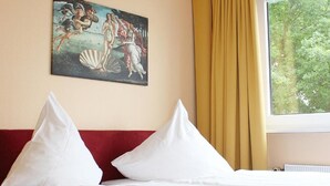 Habitación de hotel con cama, un cuadro en la pared y una ventana con cortinas.