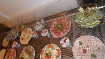 A variety of food items displayed on a metal tray, including plates of sliced meats, cheeses, and vegetables.