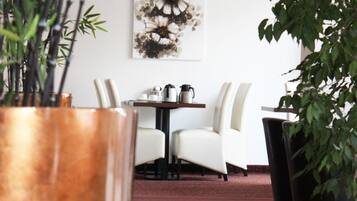 A dining area with a table and chairs, a large potted plant, and a wall-mounted artwork.
