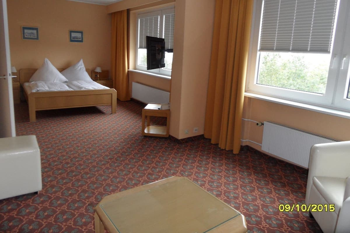 A hotel room with a bed, a desk, a chair, and a window with curtains.