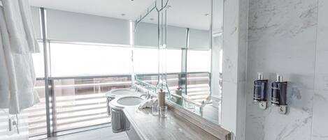 A modern bathroom with a large mirror, two sinks, and a glass shower enclosure.