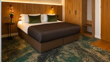 Un dormitorio con una cama grande, un armario de madera y una mesita de noche con un florero.