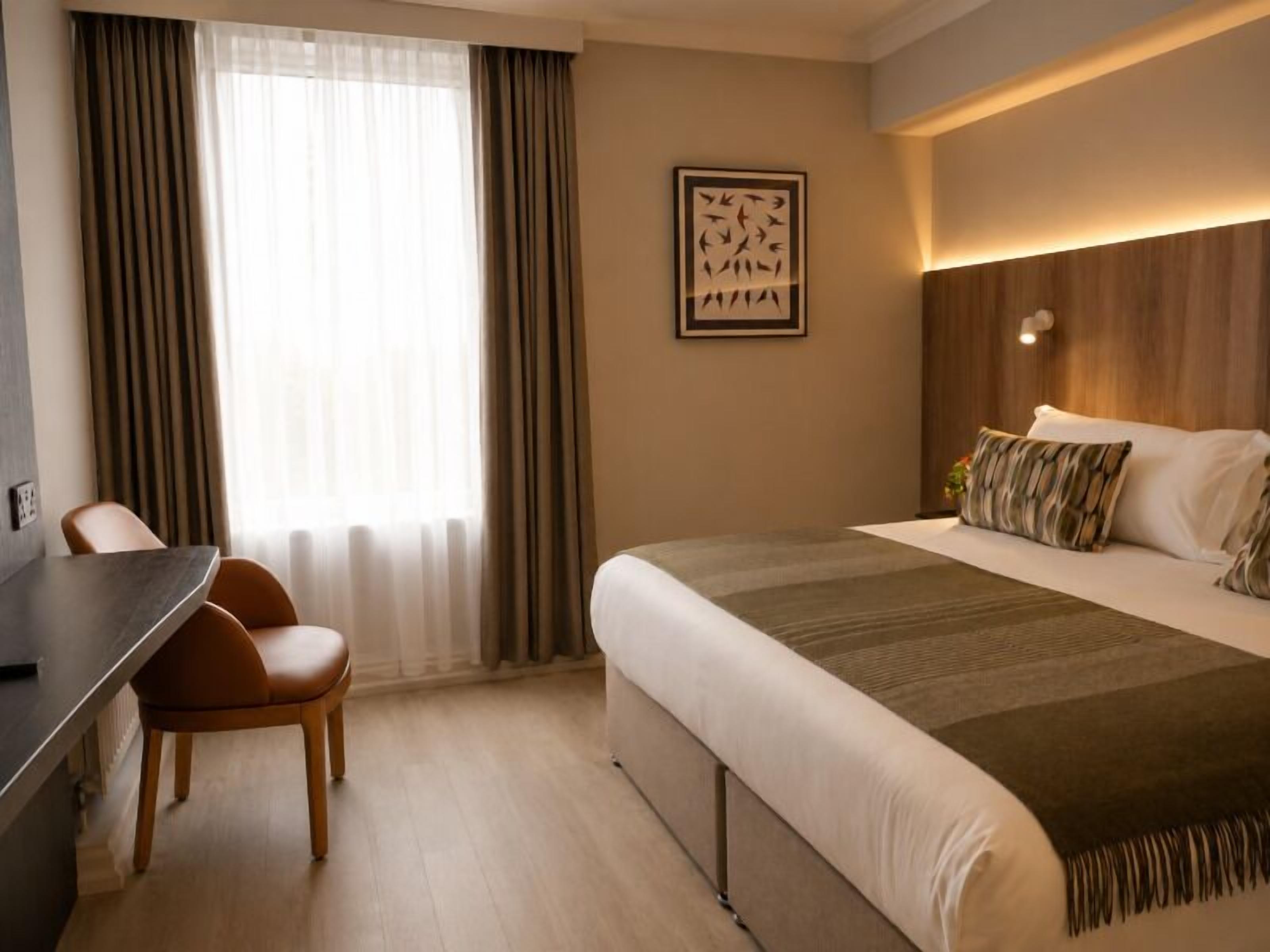 Una habitación de hotel con cama, escritorio y silla.