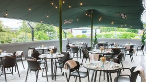 An outdoor dining area with round tables and chairs, covered by a green canopy with string lights. - Talbot Hotel Clonmel (Clonmel)