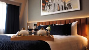 A neatly made bed with a tray of glasses and a bottle, a framed picture on the wall, and a window with curtains. - Talbot Hotel Clonmel (Clonmel)