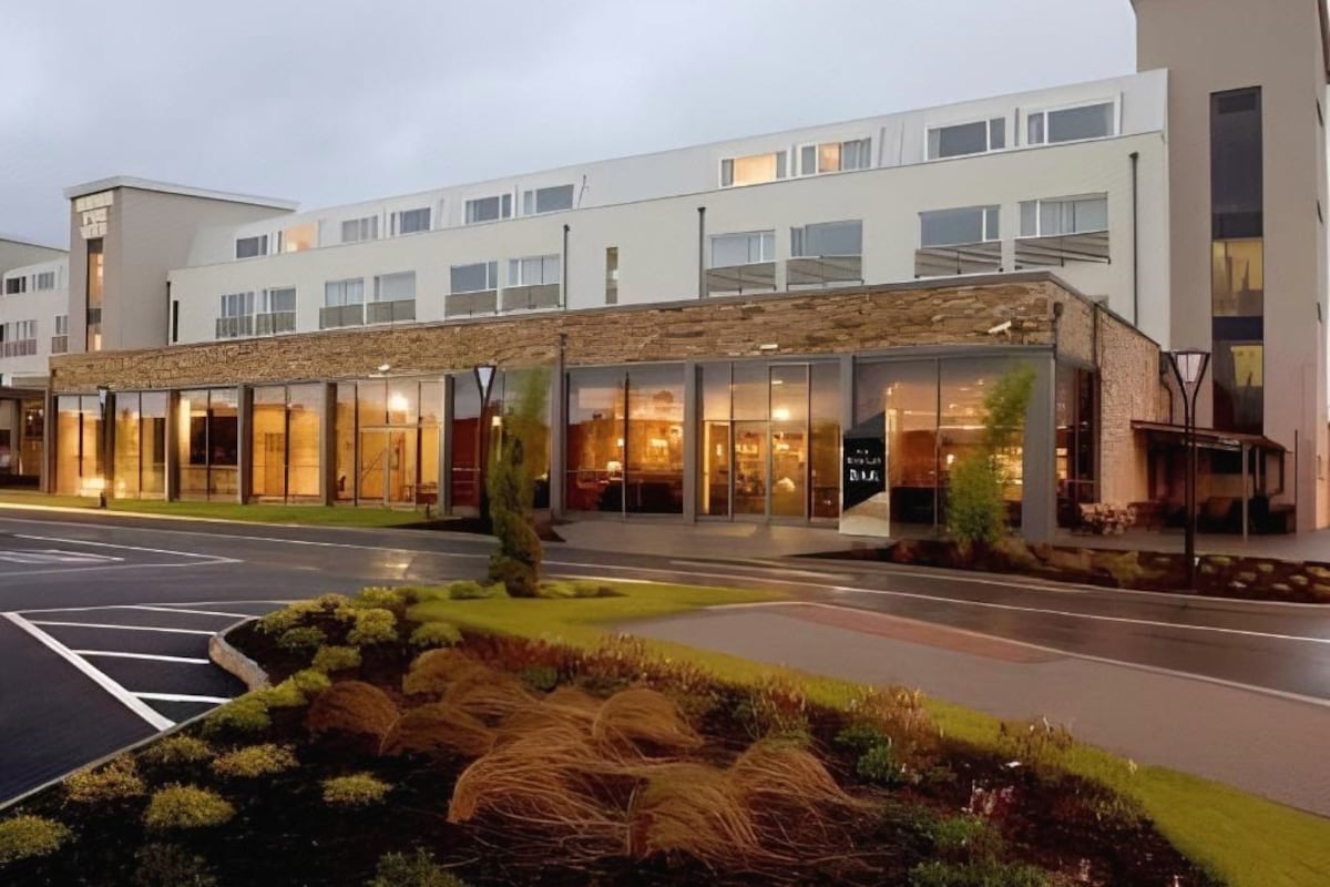 A modern hotel with a stone facade, large windows, and a well-maintained outdoor area.