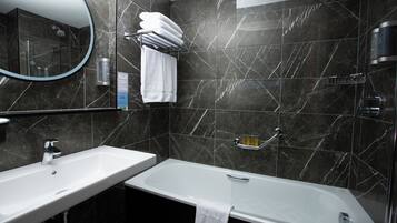 Un baño moderno con un lavamanos blanco, una bañera y un espejo grande.