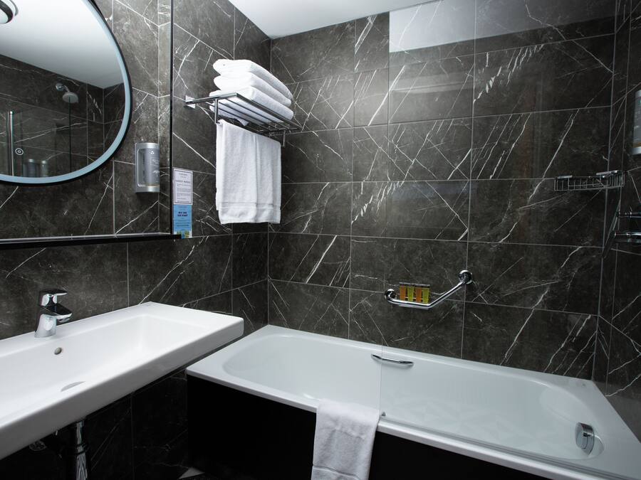 Ein modernes Badezimmer mit einem weißen Waschbecken, einer Badewanne und einem großen Spiegel.