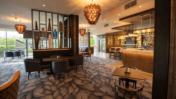 A modern hotel lobby with a bar area, seating arrangements, and a patterned carpet. - Talbot Hotel Clonmel (Clonmel)