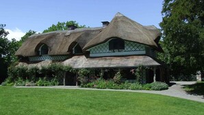 A thatched-roof cottage with a green exterior and a small garden in front. - Talbot Hotel Clonmel (Clonmel)
