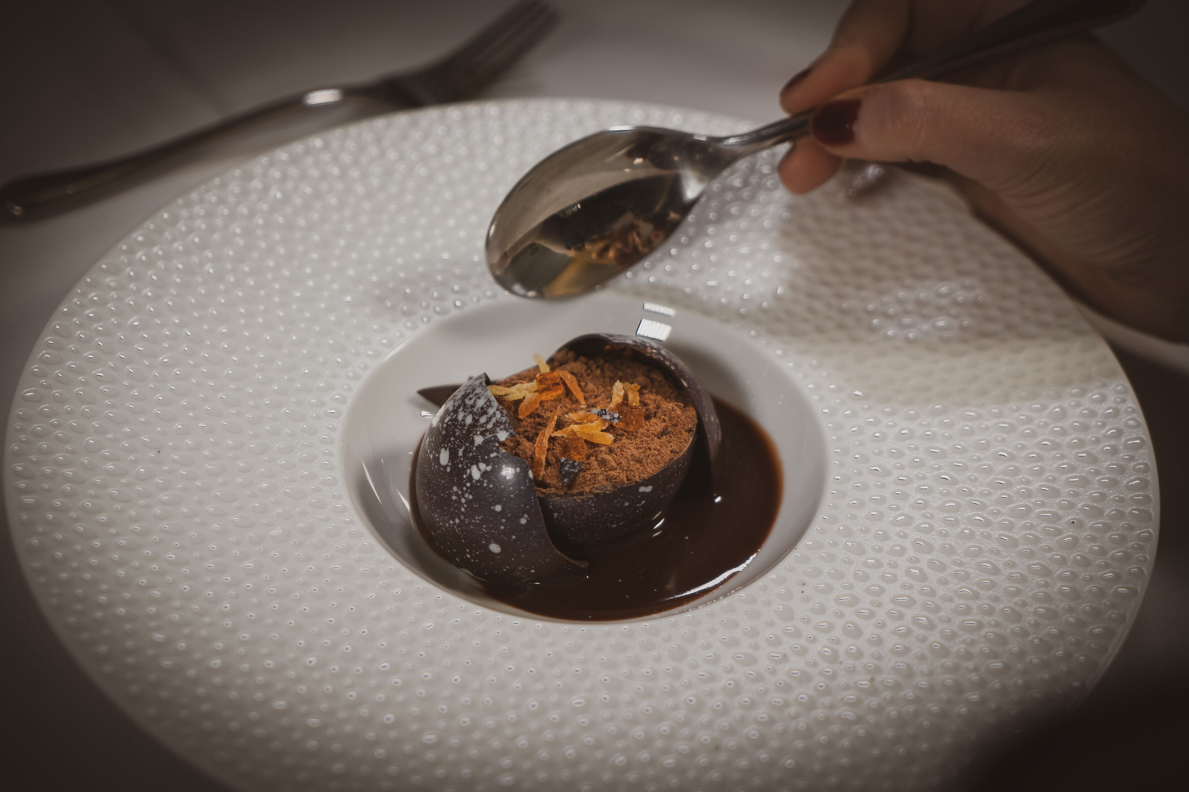 Un postre en un plato blanco con textura y una cuchara.