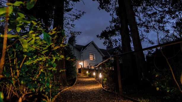 Een huis met een pad dat ernaartoe leidt, omringd door bomen.
