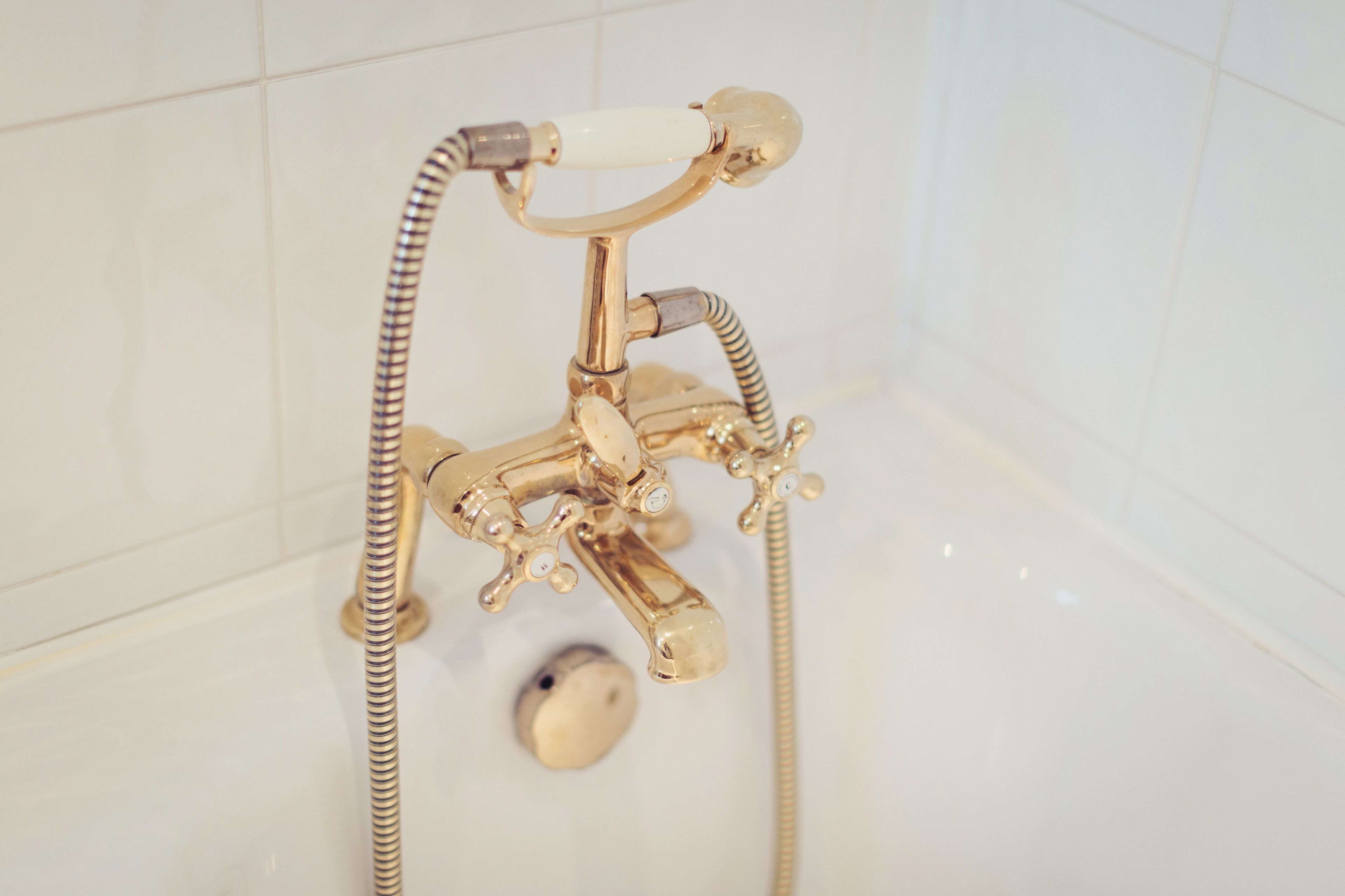 Eine goldfarbene Badezimmerarmatur mit Duschbrause und flexiblen Schlauch.