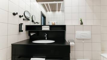 A modern bathroom with a black vanity, white tiles, a mirror, a towel rack, and a toilet.