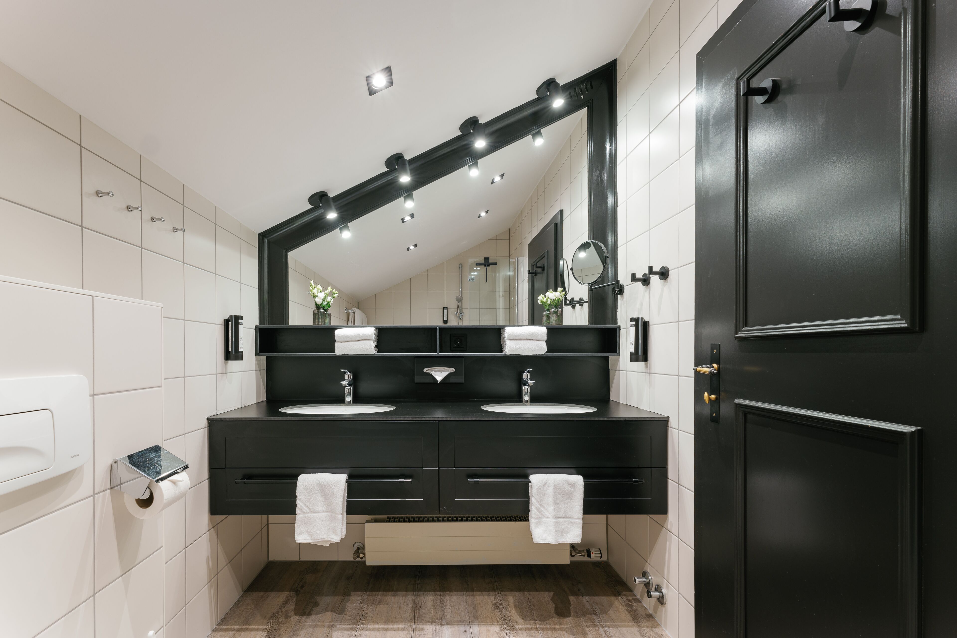 Un baño moderno con dos lavamanos, un espejo grande y un mueble de tocador negro.
