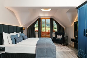 A bedroom with a large bed, a chair, a wardrobe, and a window with a view of greenery. - MONDI Hotel am Grundlsee (Grundlsee)