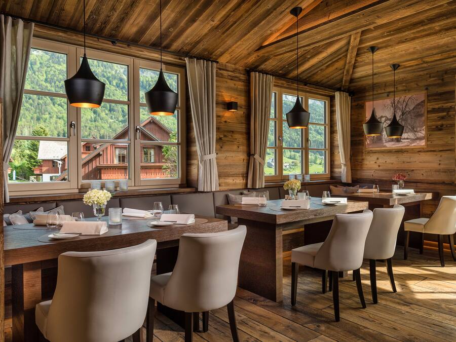 A wooden interior with a dining area, large windows, and a view of a mountain.