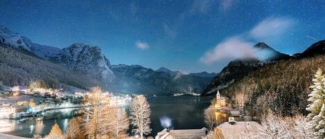 A snow-covered landscape with a lake, mountains, and a small town with buildings and a church.
