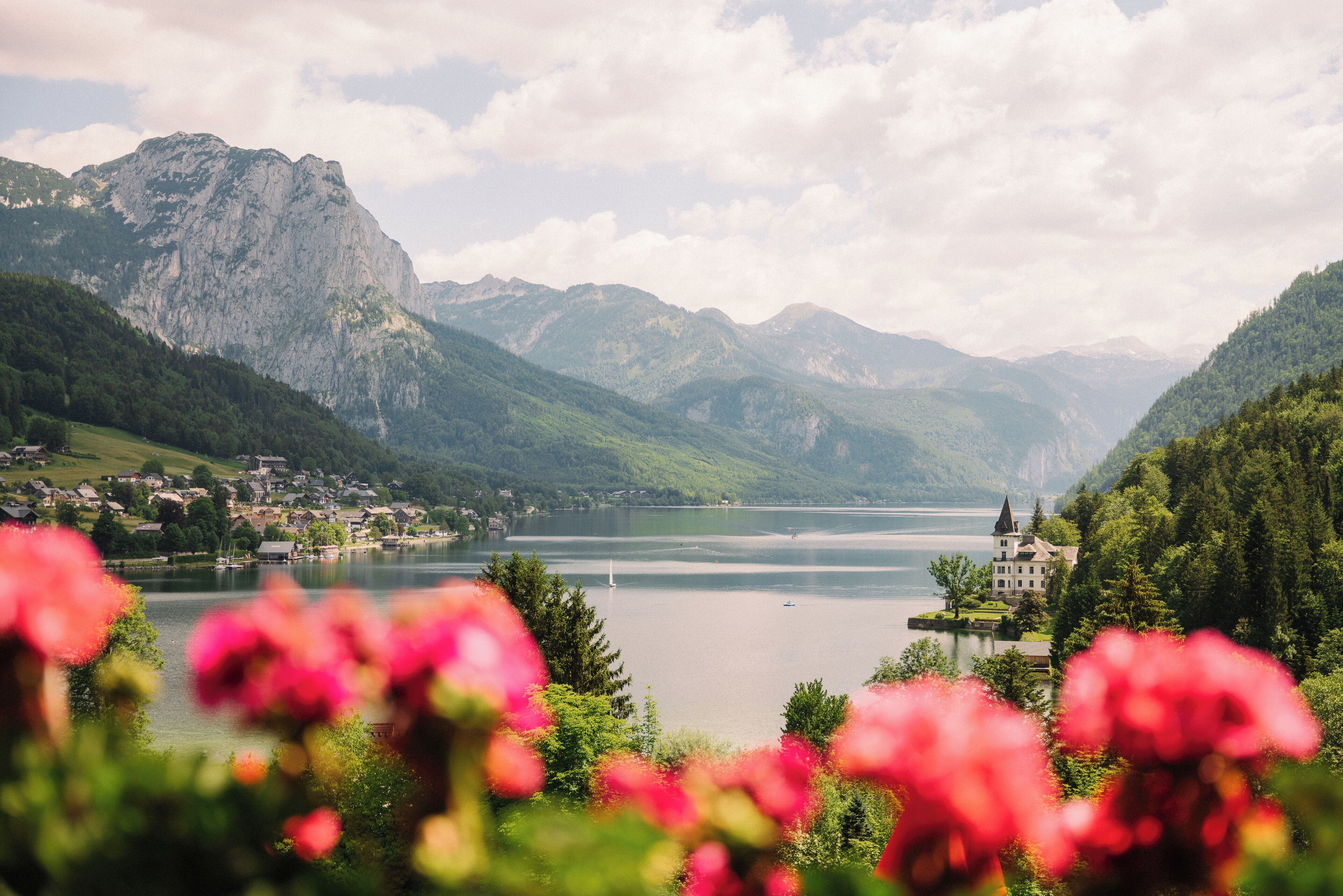 Un paysage montagneux avec un lac, une petite ville et un bâtiment imposant doté d’une tour.